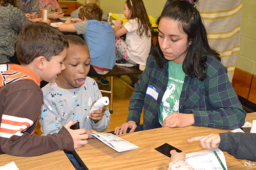 Guadalupe Herrera (right) helps youngsters who are enjoying an activity during Cena y Ciencias.