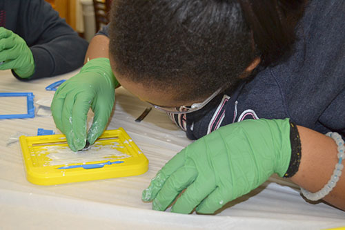 A Franklin student uses the magnet that was inside her Magnadoodle to play with the iron shavings in her toy's white suspension fluid.