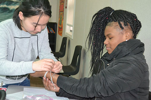 Lorenz’ PhD student, Junyi Wu ties the bracelet a Franklin student has made on her wrist. The bracelet is made from special beads that turn color after being exposed to UV light.
