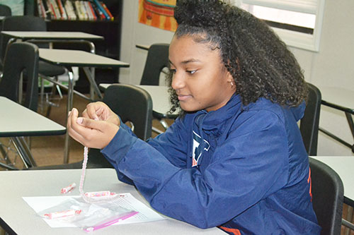 A Franklin seventh grader makes a bracelet with the beads that react to UV light.