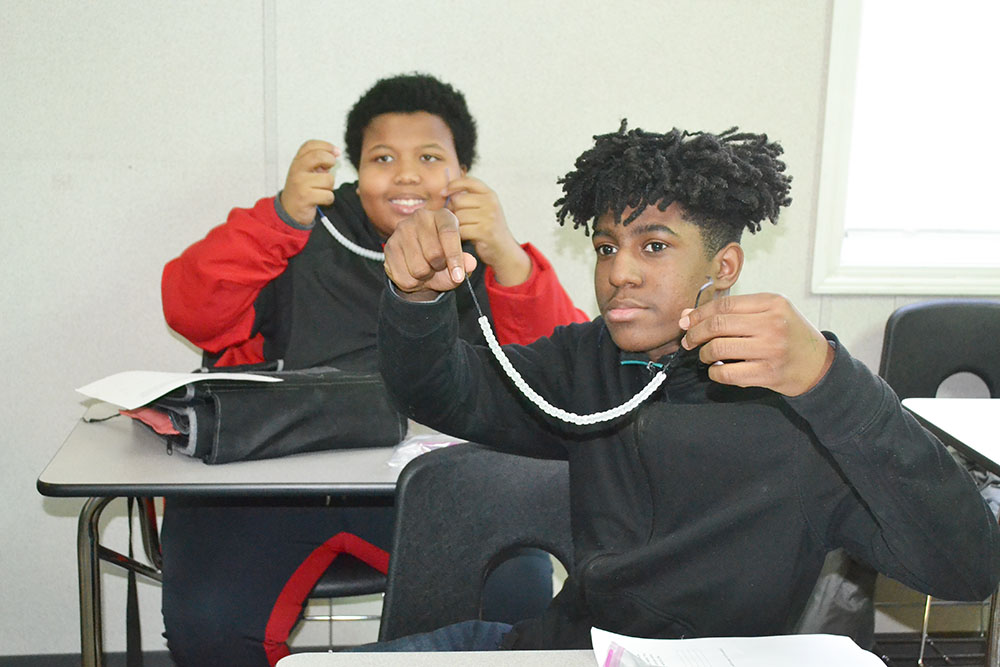 Franklin seventh graders show off the necklaces they’ve made from special beads that react to UV light.