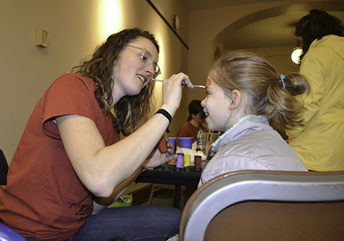 an entomology student paints the face of a local fourth grader