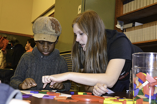 An Illinois math student (right) works on a tile puzzle with a local youngster at the Math Carnival's Tile Emporium station.