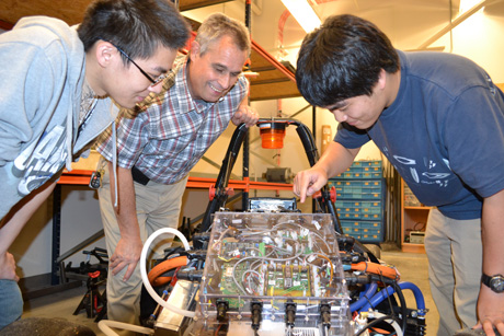 Two students and Mike Philpott examine Hybrid's circuitry