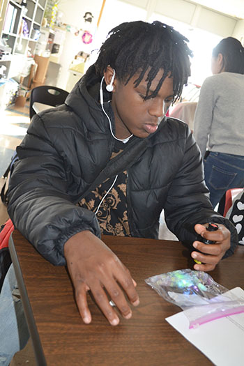 A  Franklin eighth grader shines a UV flashlight on a bag of special UV beads he  has coated with lotion to test its ability to “protect” the beads from UV rays