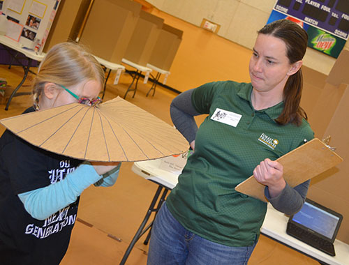 Stacey Clements, the Champaign County Forest Preserve's Education Program Specialist, watches as an NGS student demonstrates the prototype she designed for her project.