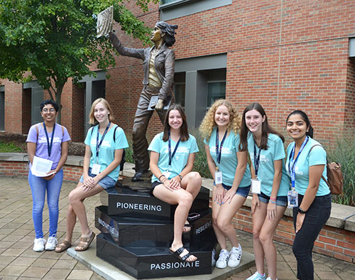A mentor (left) introduces her group to Quin (the Quintessential Engineer), the statue of the female engineering student erected on campus near MNTL a couple of years ago.