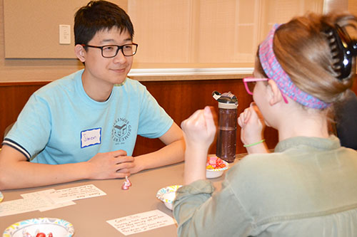 A math student, Simon Liu, interacts with a middle school visitor to the carnival