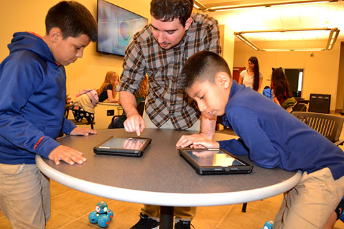 Andres Arango (center) interacts with students who are programming their Dash Robot. 