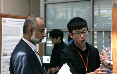 Irfan Ahmad discusses a trainee's research poster during the B3 Summer Institute
