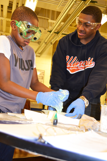 A participant at the Saturday lab session makes slime, assisted by one of the program's mentors.