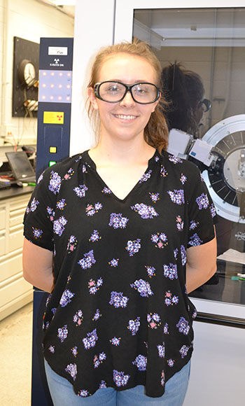 I-MRSEC undergrad Carmen Paquette by one of the instruments she learned to use in Daniel Shoemaker's lab.