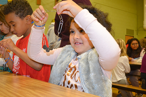 A young Cena y Ciencias visitor with their paper clip chain.