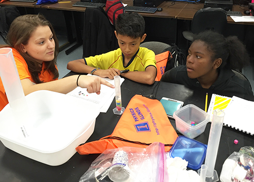  An <em>Illinois</em> Engineering student interacts with two Chicago youngsters during a hands-on activity.