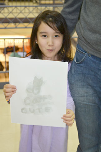 A youngster shows off her work at the invisible ink activity.