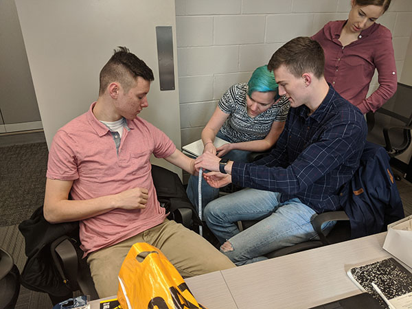 Isaac Husemann (seated right) and other members of Team 36 take measurements in order to ensure that Dylan Taylor (seated left) gets a comfortably-fitting aparatus. (Photo courtesy of Isaac Husemann.)