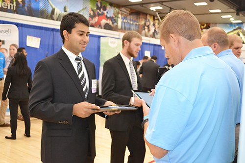 Two <em>Illinois</em> engineering students (left) chat with recruiters from Texas Instruments.