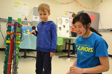 Illinois student Kaylin Moy does a Physics Coaster exhibit with a youngster. While playing, he learned a bit about potential energy, kinetic energy, and friction.