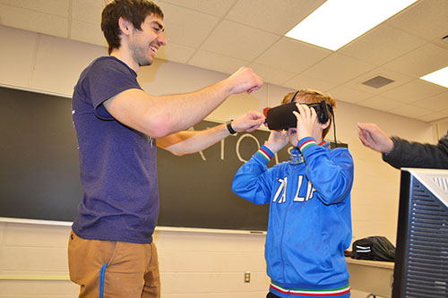 MechSE Ph.D. student Kyle Mackay helps adjust the VR equipment on his first young visitor: 10-year-old William Johnson.