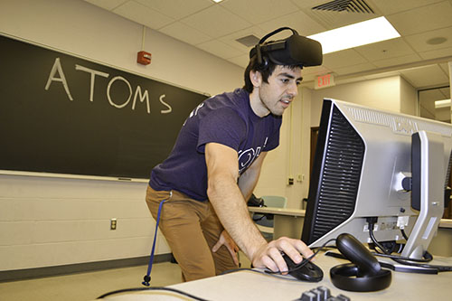 Kyle Mackay, MechSE Ph.D. student, sets up a virtual reality experience about atoms in motion for EOH visitors to try.