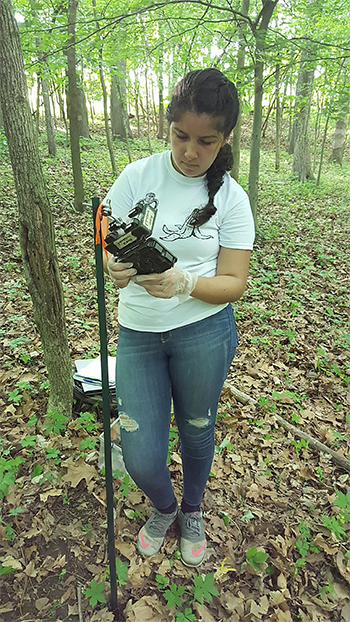 Alondra Estrada setting up a camera out in the woods where she studied turtles.