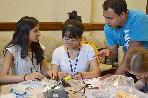 Sameer Muckatira (upper right) works with GBAM campers during the copper-tape-circuit activity.