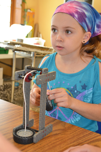 Fourth grader works on the pulley she and her team made from a VEX kit.
