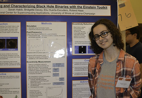 Sarah Habib proudly stands in front of her research project on Black Hole Binaries.
