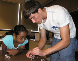 Uni camp counselor helps camper with her project.