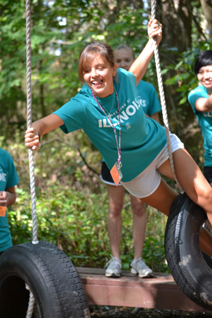 Camper traversing the tire swing station on the Challenge Course.