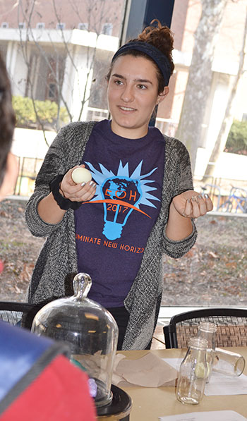 <em>llinois</em> physics student Hannah Manetsch prepares to use physics to get the egg in the bottle.
