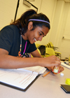 Camper uses a ph strip to test a water sample during a hands-on activity exploring water purity.