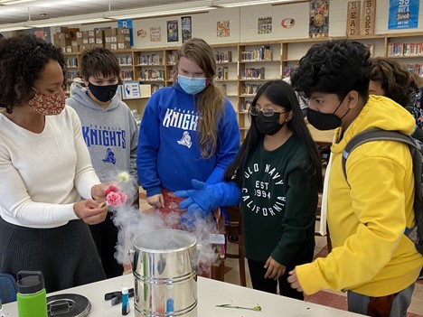 Eighth-grade students at Franklin STEAM Academy watch as University of Illinois Physics Professor Nadya Mason submerges carnations in a canister of liquid nitrogen in the Champaign middle school’s library.
